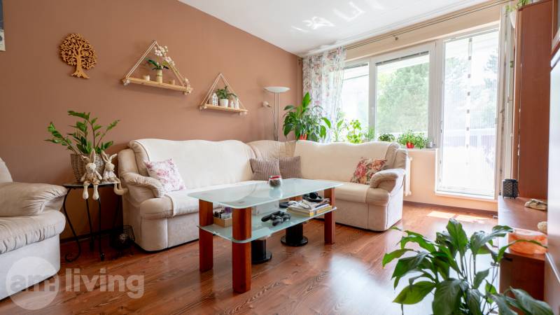 Helles Wohnzimmer in einer 3-Zimmer-Wohnung mit Blumendekoration und bequemer Couch.