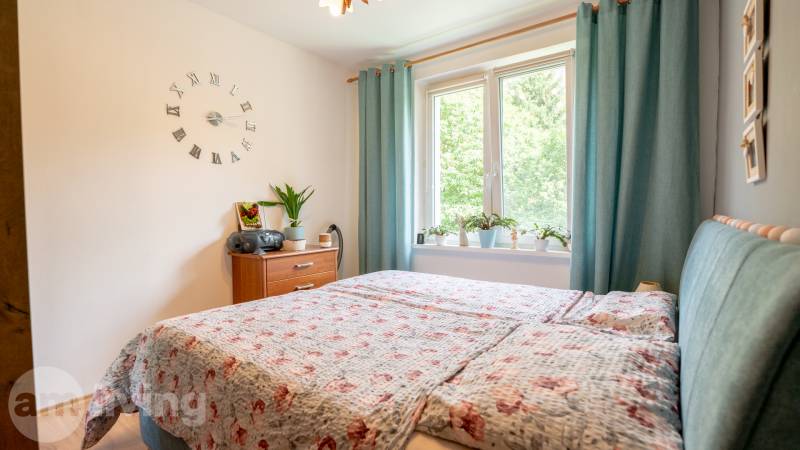 Schlafzimmer in einer 3-Zimmer-Wohnung mit Bett, Nachttisch und Dekorationspflanzen.