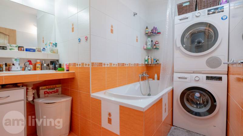 Badezimmer in einer 3-Zimmer-Wohnung mit Waschmaschine und Trockner, orange Fliesen, Badewanne.