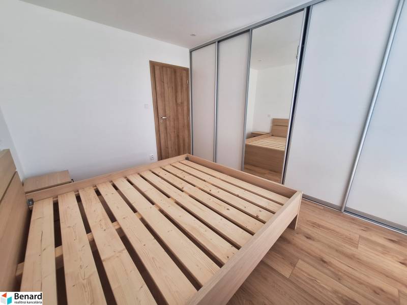 Schlafzimmer mit einem Holzbett und einem Einbauschrank in einer 2-Zimmer-Wohnung.