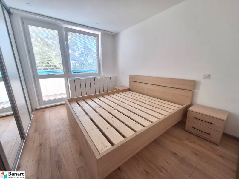 Helles Schlafzimmer mit Holzbett und Nachttischen in einer 2-Zimmer-Wohnung.