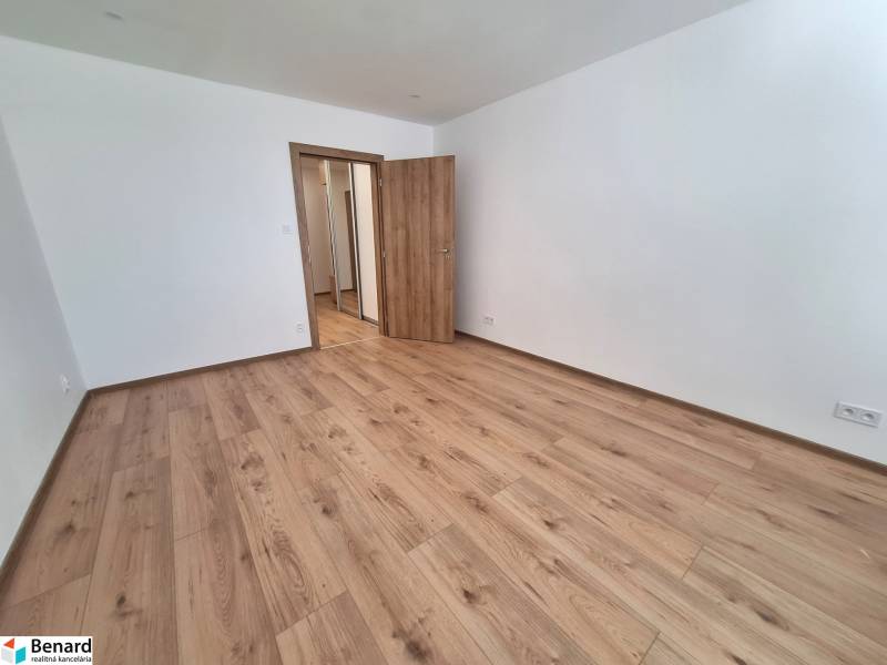 Ein leerer Raum mit Holzboden und geschlossenen Türen in einer Zweizimmerwohnung.