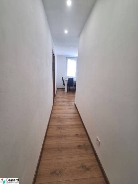 Flur in einer 2-Zimmer-Wohnung mit Holzboden und Deckenleuchten.