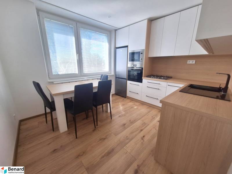 Küche in einer 2-Zimmer-Wohnung mit Esstisch, Herd und Geräten.
