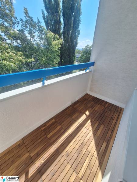Balkon mit Holzboden und Blick auf Bäume in einer 2-Zimmer-Wohnung.