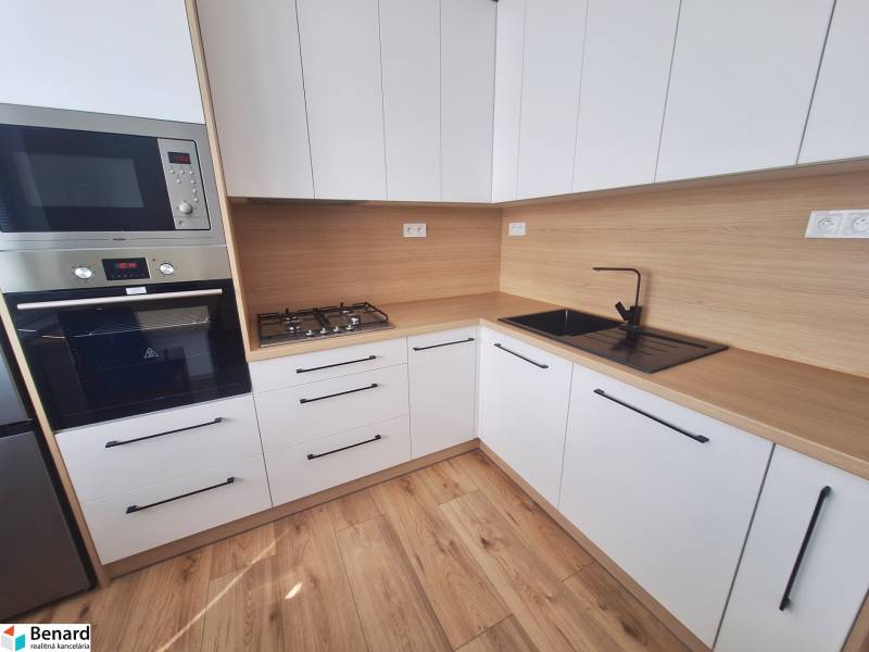 Küche in einer 2-Zimmer-Wohnung mit Holzboden und eingebauten Geräten.