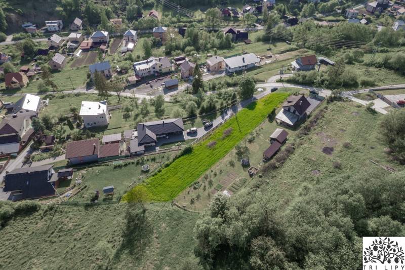 Luftaufnahme von Wohngebieten in der Gemeinde Raková, grüne Hänge und Häuser.