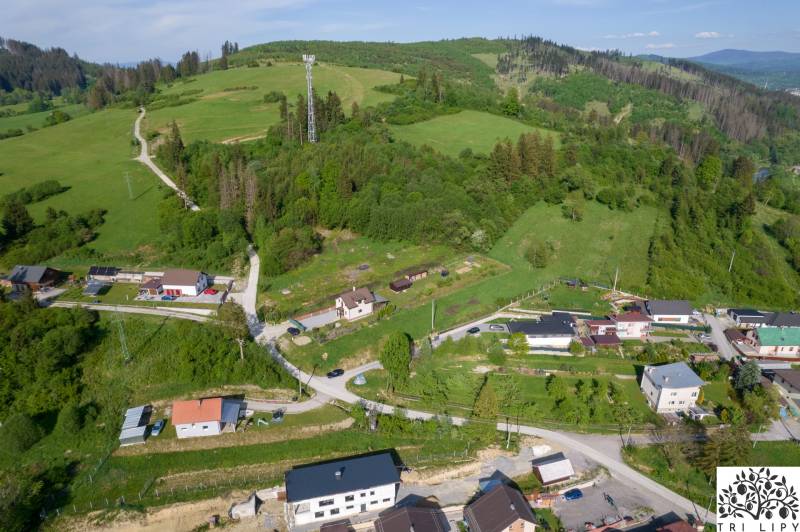 Luftaufnahme von Wohnbaugrundstücken in Raková, umgeben von grünen Hügeln und Häusern.