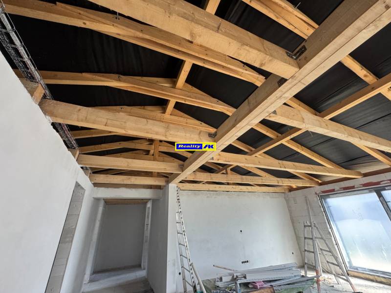 Das Einfamilienhaus hat weißen Putz, Holzbalken und eine unvollendete Decke.