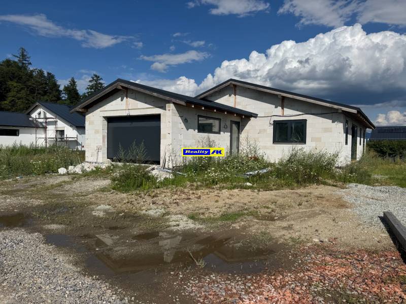 Unvollendetes Einfamilienhaus in Valča mit Garage, umgeben von Natur und Baumaterialien.