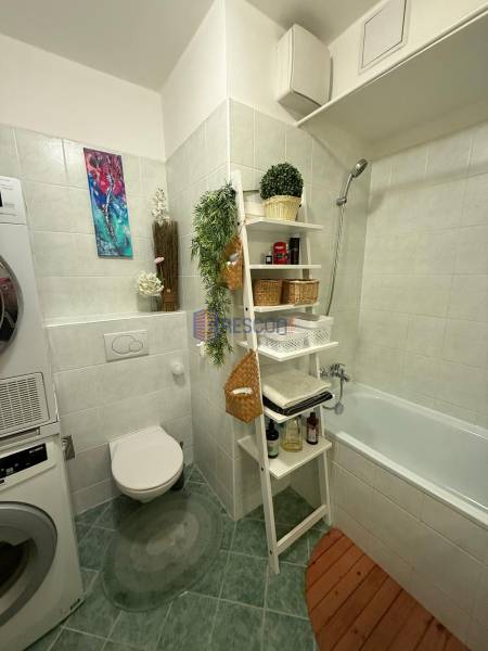 Badezimmer mit Waschmaschine, Badewanne und Dekorationen in einer 2-Zimmer-Wohnung.