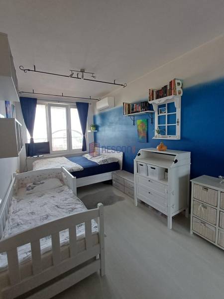 Kinderzimmer mit zwei Betten, blauer Wand und viel Stauraum.