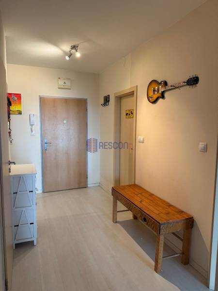 Eingangsflur in einer Zweizimmerwohnung mit einer Holzbank und einer dekorativen Gitarre an der Wand.