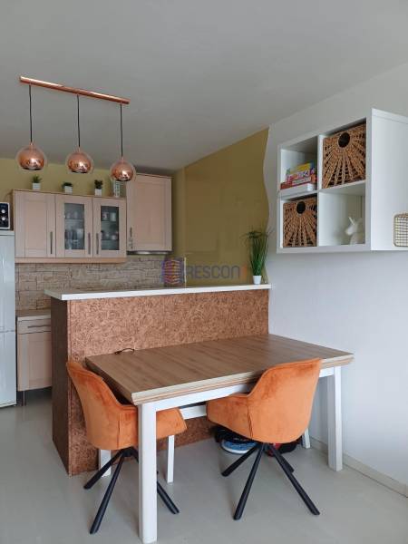 Essbereich in einer 2-Zimmer-Wohnung mit orangefarbenen Stühlen und Hängelampen.