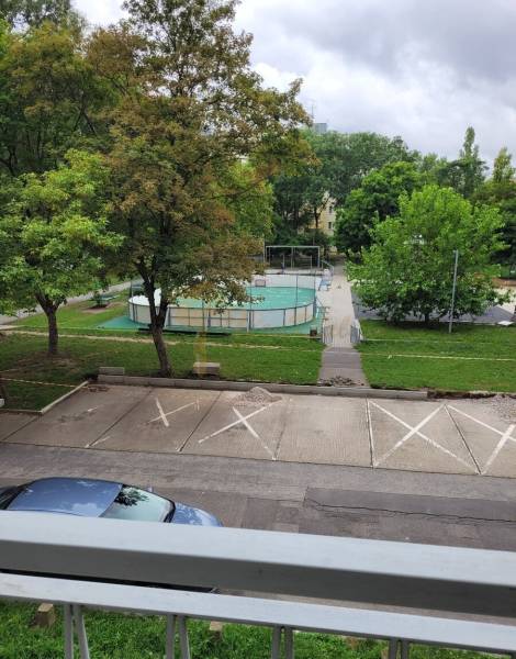 Blick aus einer 3-Zimmer-Wohnung in Bratislava - Ružinov auf der Mesačná-Straße, Parkplatz, Bäume und Spielplatz.