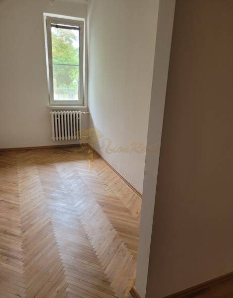 Ein Zimmer in einer 3-Zimmer-Wohnung mit Holzboden und einem Heizkörper unter dem Fenster.