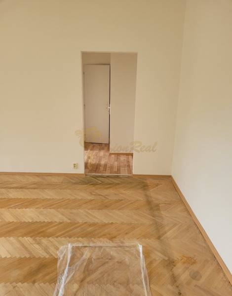 Ein Zimmer mit Holzboden und weißer Wand in einer 3-Zimmer-Wohnung.