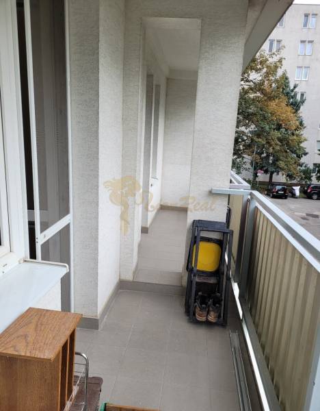 Ein Balkon in einer 3-Zimmer-Wohnung mit Klappstühlen und Blick auf die Bäume im Hof.