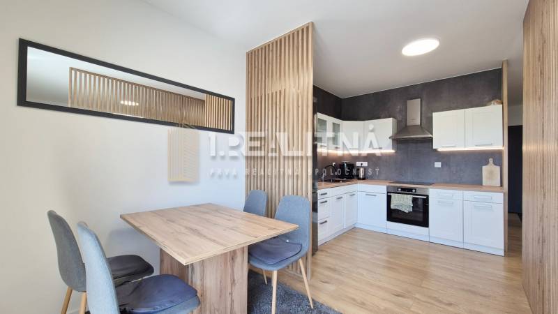 Die Küche in einer 4-Zimmer-Wohnung mit einem Ess-Set aus Holz und weißen Schränken.