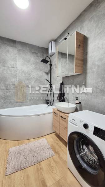 Badezimmer in einer 4-Zimmer-Wohnung mit Eckbadewanne und Waschmaschine.