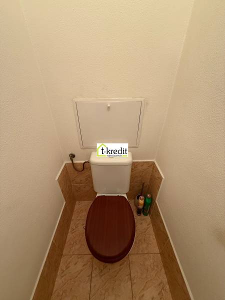 Toilette mit braunem Sitz und Fliesen in einer 2-Zimmer-Wohnung.