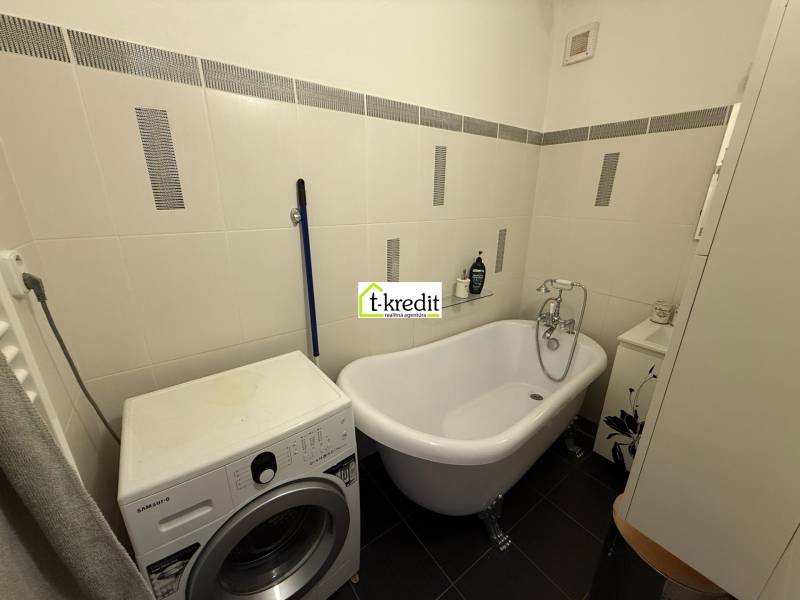 Badezimmer in einer 2-Zimmer-Wohnung mit freistehender Badewanne und Waschmaschine.