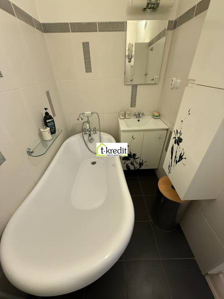 Badewanne im Badezimmer mit Duscharmatur und Waschbecken in einer 2-Zimmer-Wohnung.