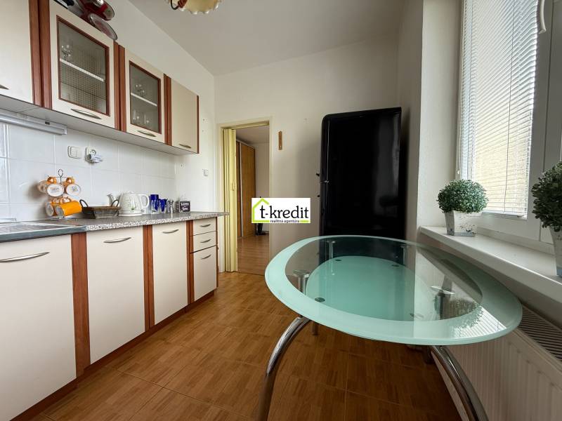 Küche in einer 2-Zimmer-Wohnung mit einem Glastisch und weißen Schränken.