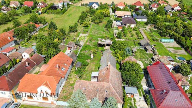 Luftaufnahme des Wohngebiets in Báč, umgeben von Grünflächen und Häusern.