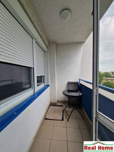 Balkon mit Außensitzbereich in einer 2-Zimmer-Wohnung. Rollos an den Fenstern.