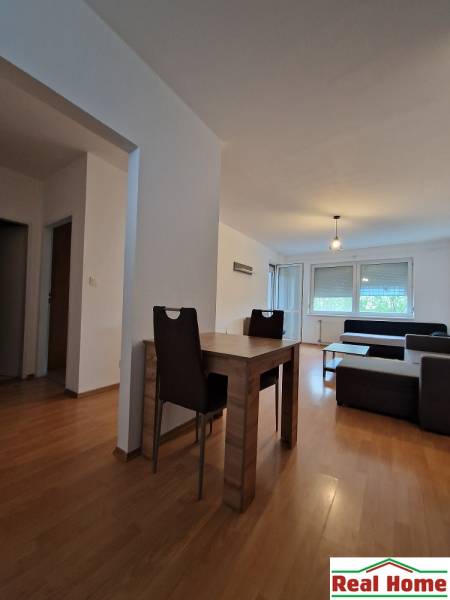 Esstisch mit Stühlen im Wohnzimmer einer Zweizimmerwohnung mit Holzboden.