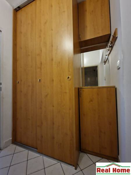 Ein Einbauschrank aus Holz mit weißen Fliesen auf dem Boden in einer 2-Zimmer-Wohnung.