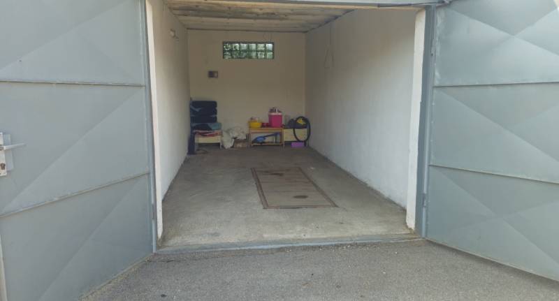 Offene Garage in Nová Dubnica in der Topoľová-Straße mit verschiedenen Gegenständen und Betonboden.