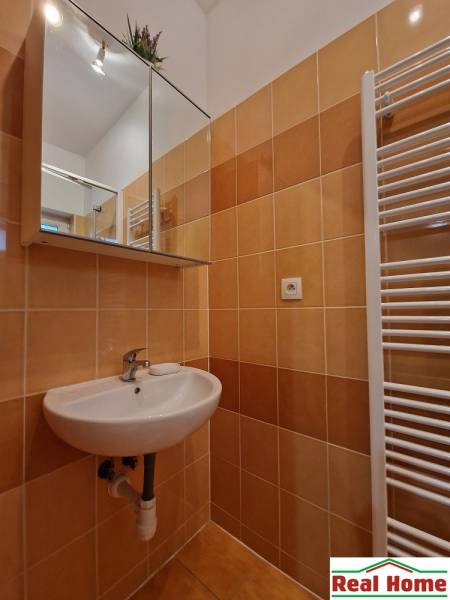 Badezimmer in einer Einzimmerwohnung mit Spiegel und Waschbecken, gefliest.