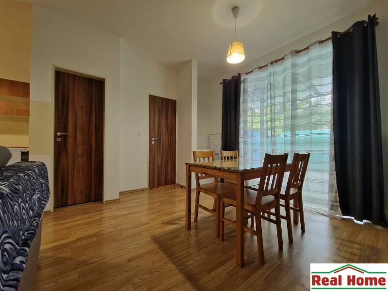 Esszimmer in einer Einzimmerwohnung mit Holzmöbeln und Glastüren.