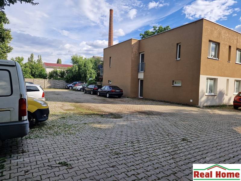 Parkplatz in der Tehelna-Straße in Pezinok mit Autos und einem Gebäude, Platz für eine Einzimmerwohnung.