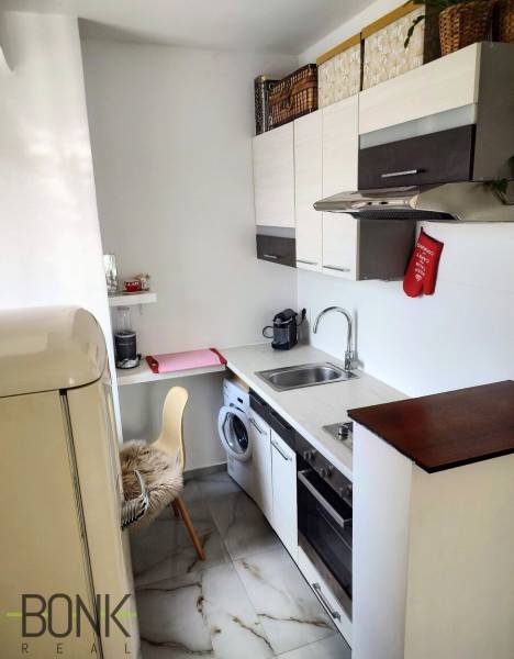 Küche in einer 2-Zimmer-Wohnung mit Kühlschrank, Geschirrspüler, Schränken und Geräten.