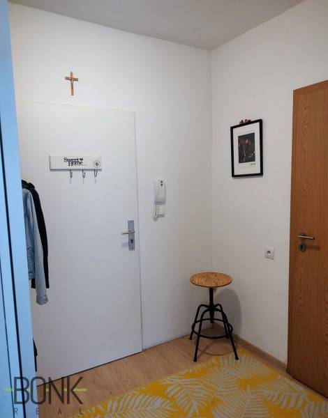Der Flur einer 2-Zimmer-Wohnung mit Garderobe, Stuhl und Teppich.