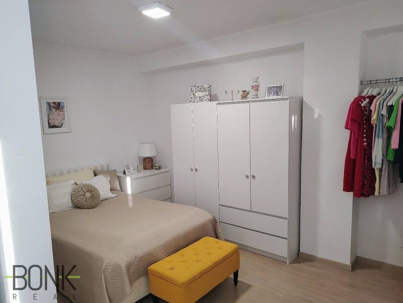Helles Schlafzimmer in einer 2-Zimmer-Wohnung mit Kleiderschrank, Bett und bunten Möbeln.