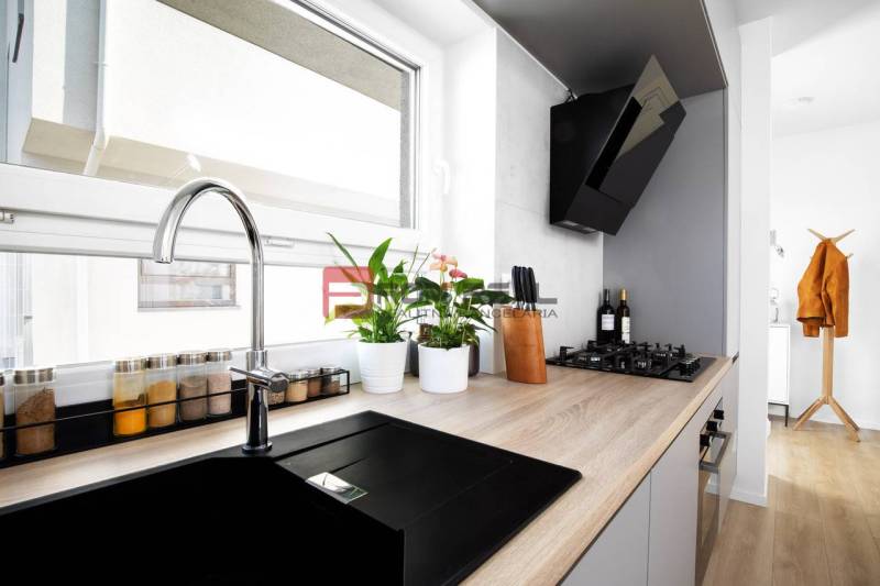 Küche in einer 3-Zimmer-Wohnung mit eingebautem Kochfeld und Pflanzen auf der Fensterbank.