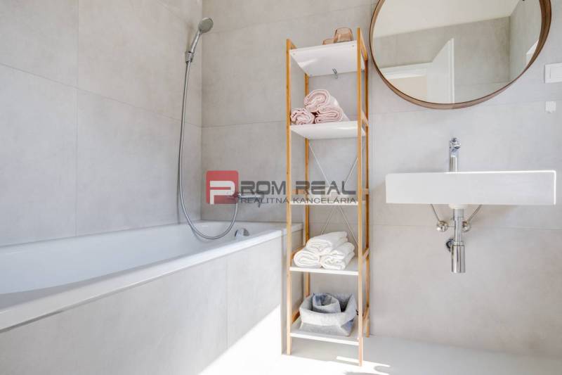 Badezimmer in einer 3-Zimmer-Wohnung mit Badewanne, offenem Regal und Spiegel an der Wand.