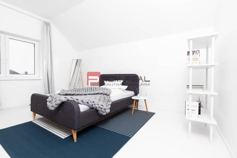 Schlafzimmer in einer 3-Zimmer-Wohnung mit modernem Bett, Regal und weißen Wänden.