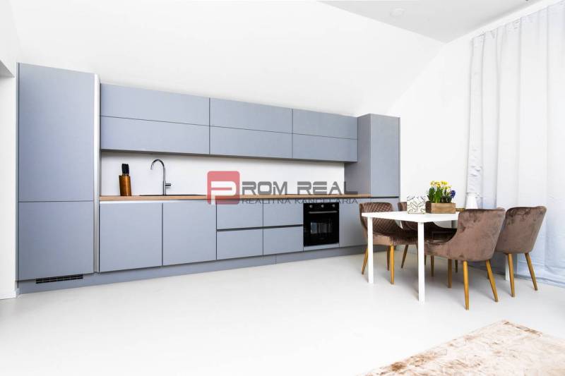 Küche in einer 3-Zimmer-Wohnung mit modernen Möbeln und einem Esstisch mit drei Stühlen.