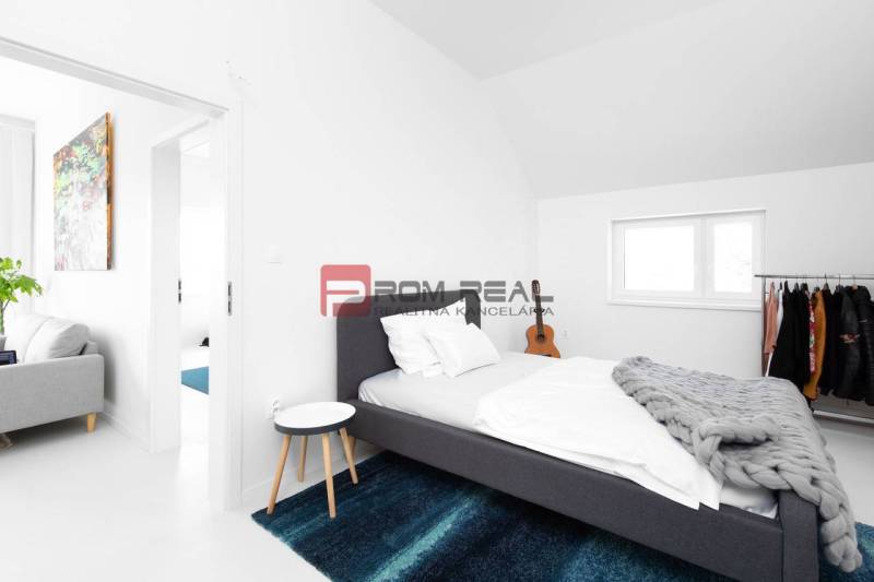 Ein Schlafzimmer mit Bett, blauem Teppich und Kleiderständer in einer 3-Zimmer-Wohnung.