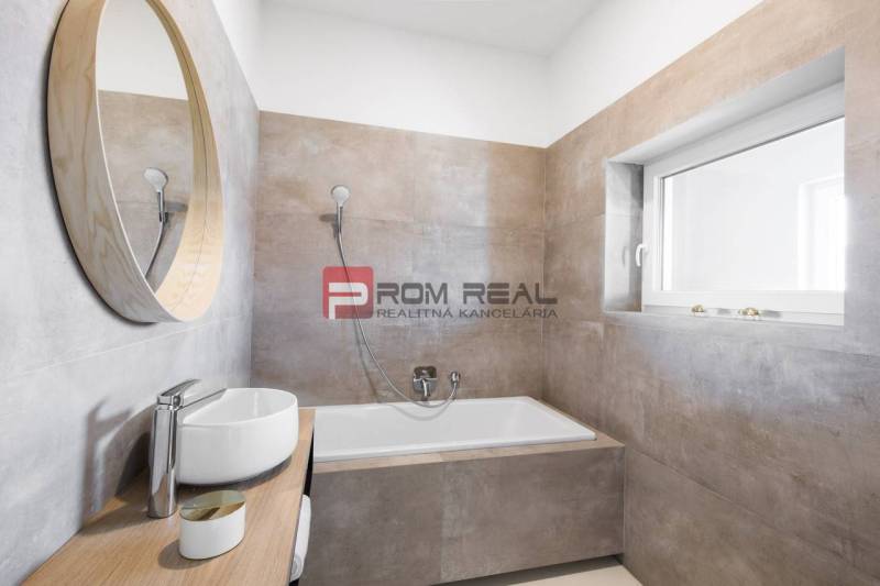 Ein Badezimmer mit Badewanne und Waschbecken in einer 3-Zimmer-Wohnung, Einfachheit und helle Töne.