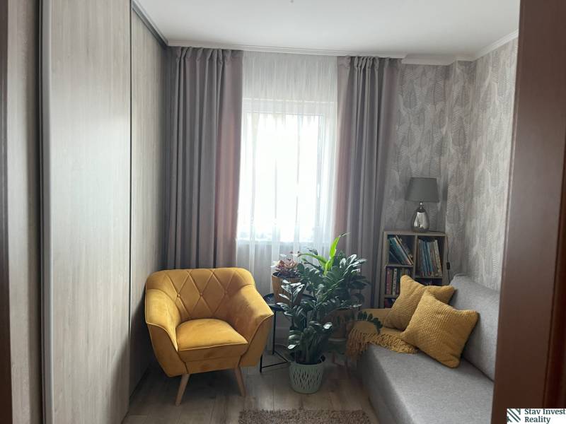 Gemütliches Zimmer in einer 2-Zimmer-Wohnung mit Sessel, Sofa und Pflanzen.
