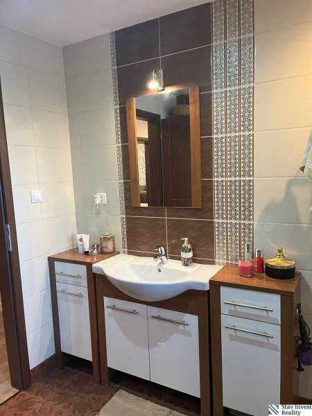 Waschbecken mit Spiegel im Badezimmer einer 2-Zimmer-Wohnung, Keramikfliesen mit Ornamenten.