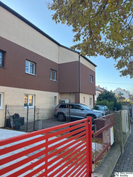 Zweistöckiges Wohnhaus in Bratislava - Ružinov, mit Parkplatz und rotem Zaun.