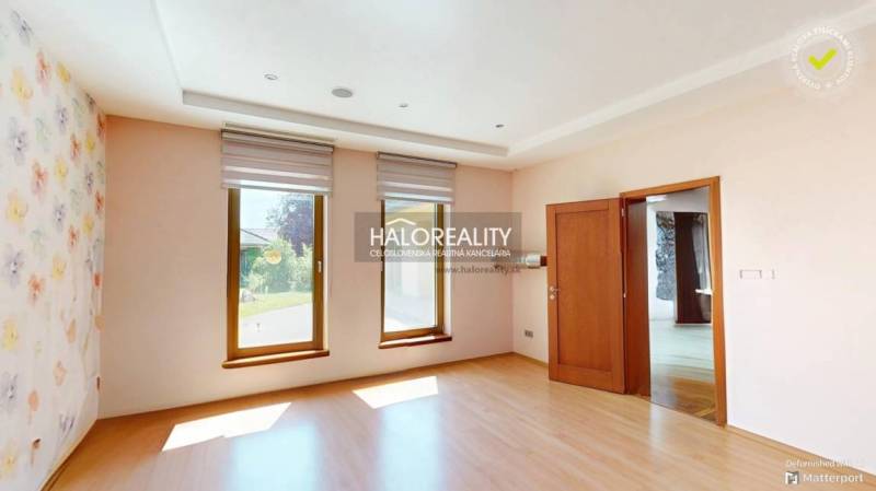 Helles Zimmer in einem Einfamilienhaus mit Holzboden und Tapete mit Blumenmuster.