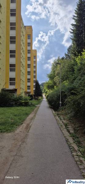 Gelbes Wohnhaus in der Moskauer Straße in Banská Bystrica neben dem Gehweg und dem Grün.